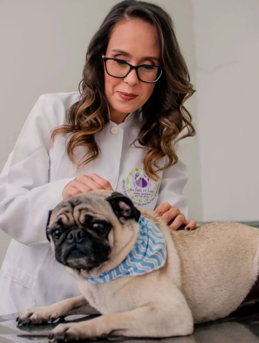 Dra. Gládis Costa em atendimento com um cachorro pug